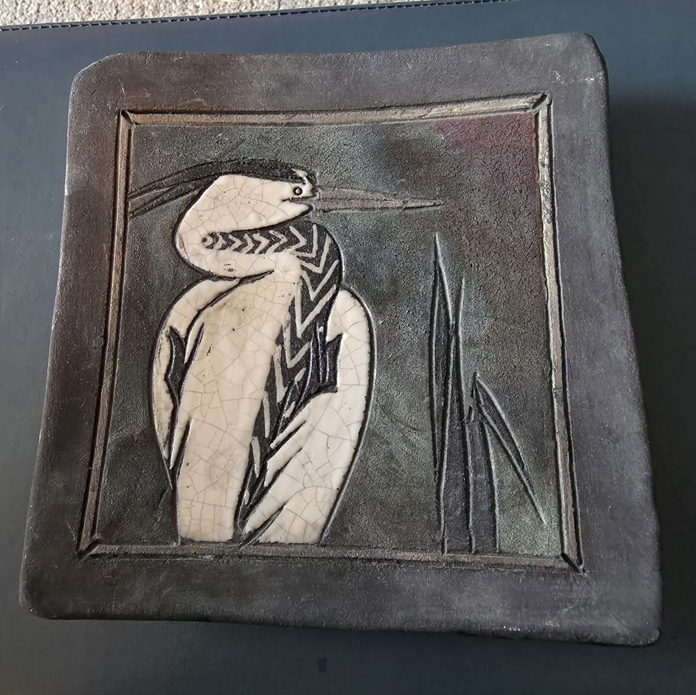 Ceramic relief plaque featuring a heron. It is a piece of decorative wall art. 